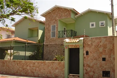 Fachada de residência com muro de pedra e casa verde